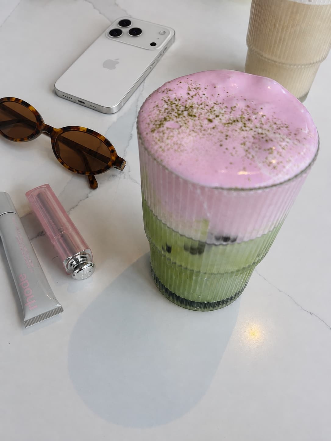A pink strawberry foam sitting on an iced green matcha latte